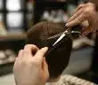 a person cutting another persons hair with a pair of scissors