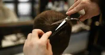 a person cutting another persons hair with a pair of scissors