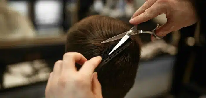 a person cutting another persons hair with a pair of scissors